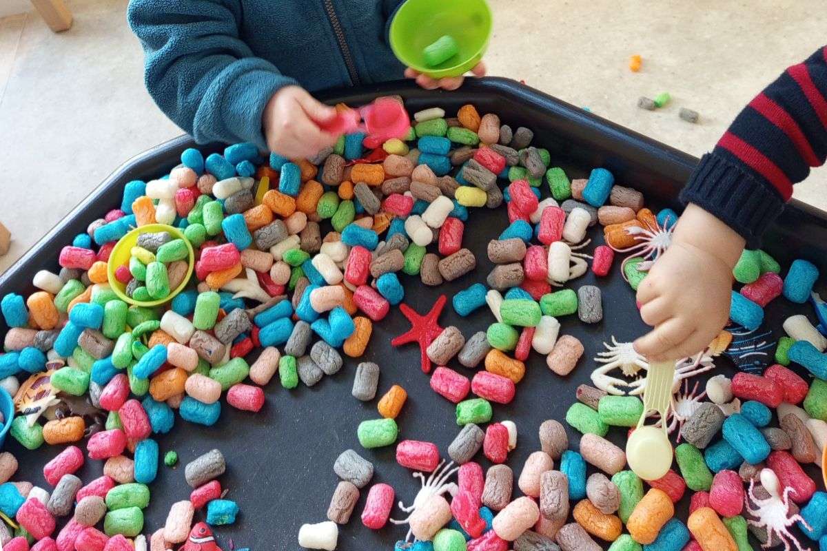 Un enfant joue avec un jeu coloré dans une salle de crèche avec des activités adaptées.